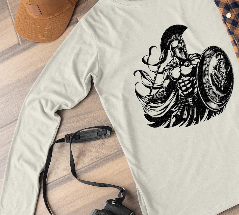 K&ouml;nnte beinhalten: Ein Langarmshirt mit einem schwarz-wei&szlig;en Grafikdruck eines spartanischen Kriegers, der eine Lanze und einen Schild h&auml;lt. Der Krieger tr&auml;gt einen Helm und einen Umhang.