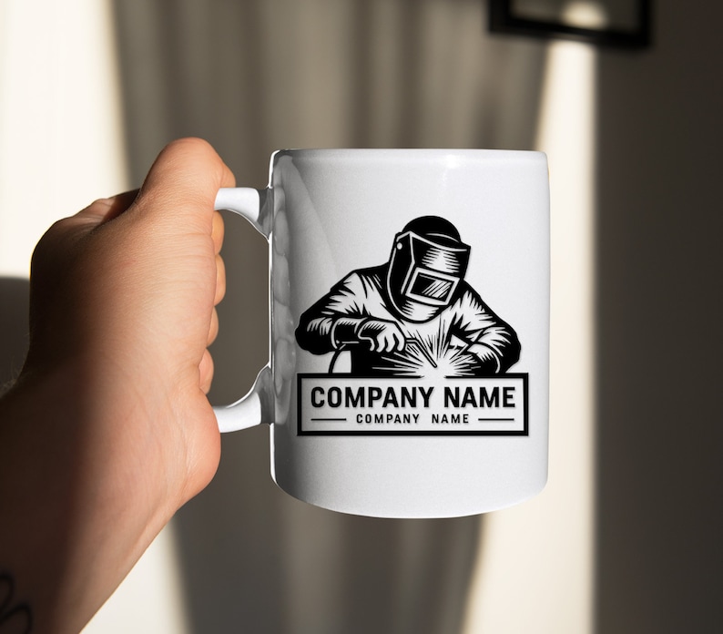 Op de afbeelding: Witte keramische mok met een zwart-witte illustratie van een lasser met een lasmasker en een lasbrander. De tekst "COMPANY NAME" staat onder de illustratie.