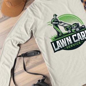 Puede incluir: Una camiseta blanca de manga larga con un logotipo de servicio de cuidado de c&eacute;sped verde y negro. El logotipo presenta a una persona cortando el c&eacute;sped con una cortadora de c&eacute;sped. El texto "LAWN CARE -SERVICE- " est&aacute; en un c&iacute;rculo negro.
