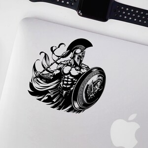 K&ouml;nnte beinhalten: Schwarz-wei&szlig;-Illustration eines spartanischen Kriegers, der einen Speer und einen Schild h&auml;lt. Der Krieger tr&auml;gt einen Helm und eine R&uuml;stung. Der Schild hat ein griechisches Design.