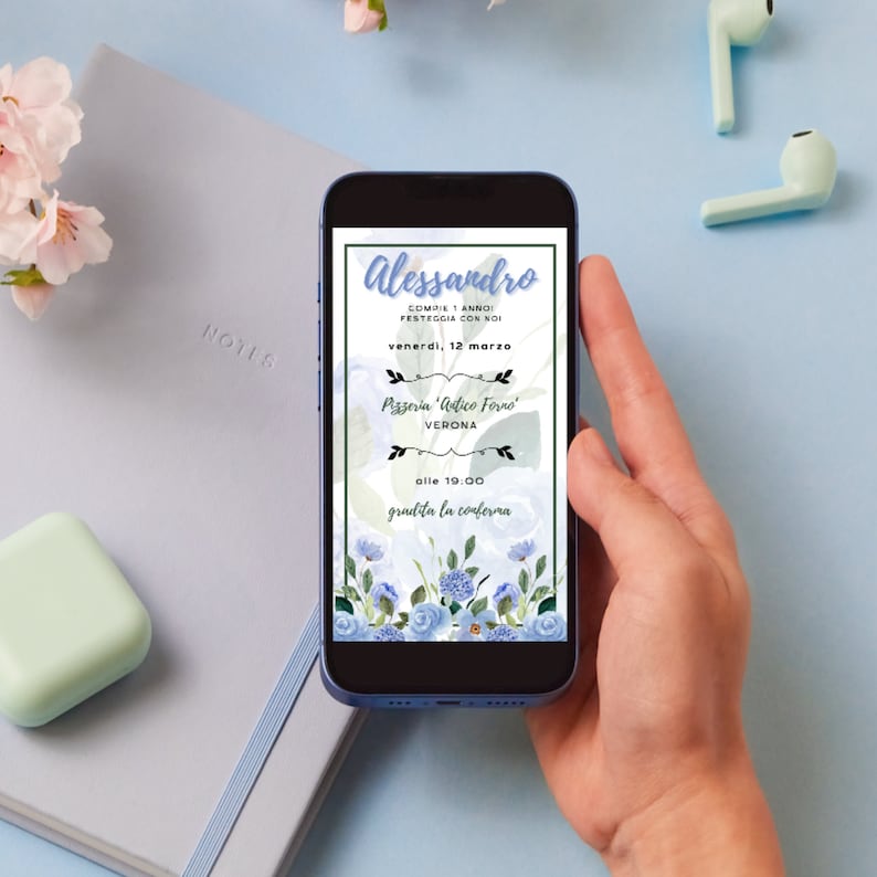 May include: A smartphone screen displaying a birthday invitation for Alessandro. The invitation features a blue floral design and the text "Alessandro Compie 1 Anno Festeggia Con Noi" (Alessandro Turns 1 Year Old Celebrate With Us). The invitation is for Friday, March 12th at 7:00 PM at Pizzeria 'Antico Forno' in Verona. RSVP is requested.