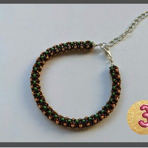 May include: A brown, green, and gold beaded bracelet with a silver clasp. The bracelet is made with small, round beads and has a simple, elegant design.