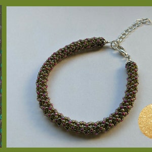 May include: A green and pink beaded bracelet with a silver clasp. The bracelet is made with small seed beads and has a subtle shimmer.