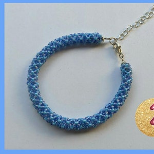 May include: A blue beaded bracelet with a silver clasp. The beads are iridescent and have a light blue color.