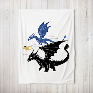 May include: A white throw blanket featuring a blue, black, and yellow dragon design. The dragons are flying in the sky with clouds.