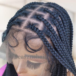 May include: A black braided wig with a lace front. The wig features numerous individual braids, meticulously arranged across the scalp. The lace front is visible, designed to blend with the wearer's skin. The text "SeasznsHair" is printed on the lace front.