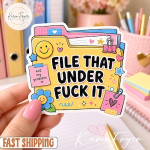 May include: A yellow file folder sticker with the black text FILE THAT UNDER FUCK IT. The design features a yellow smiley face, a blue flower with a face, pink sticky notes with text, a pink binder clip, and small star and heart icons.
