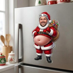 May include: A refrigerator magnet featuring a cartoon Santa Claus with a realistic face, a large exposed belly, and a red suit. The hat is inscribed with the text Mr. Smith. Santa carries a brown sack filled with colorful toys and gifts.
