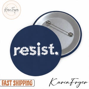 May include: A navy blue button with the word "resist." in a sparkling, diamond-like font. The button has a silver pin back and a silver rim. The button is a round shape.