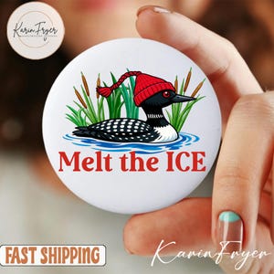 May include: A white button with a cartoon illustration of a loon wearing a red knit cap, surrounded by reeds and water. The text "Melt the ICE" is in red. The button is held by a person.