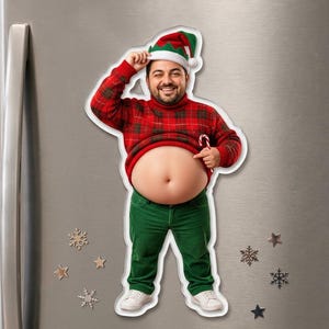 May include: A die-cut refrigerator magnet featuring a smiling person wearing a red and green plaid sweater, green pants, and a festive elf hat. The person is lifting their sweater to expose their bare stomach while holding a candy cane.