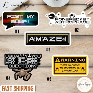 May include: A collection of humorous stickers with various designs and text. One sticker reads "FIST MY BUMP!" in a speech bubble. Other stickers include "POWERED BY ASTROPHACE", "A*MAZE!", "USUALLY YOU NOT STUPID WHY STUPID QUESTION?", and "WARNING THIS MACHINE IS POWERED BY ASTROPHACE".