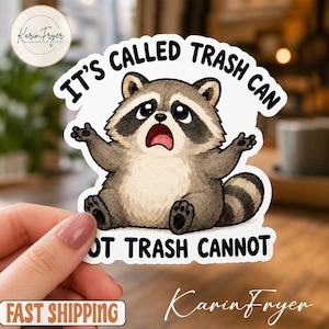 Puede incluir: Una pegatina troquelada que muestra un mapache marrón y gris con expresión de sorpresa, sentado con los brazos levantados. El texto superior dice IT'S CALLED TRASH CAN y el texto inferior dice NOT TRASH CANNOT en letras mayúsculas negras.