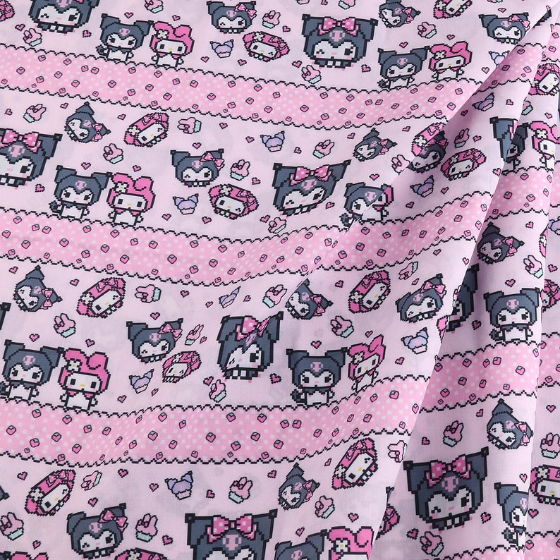 Op de afbeelding: Roze stof met een herhalend patroon van zwart-witte cartoonfiguren. De figuren dragen strikken en hebben hartjes om zich heen. De stof heeft een roze-witte stippen achtergrond.