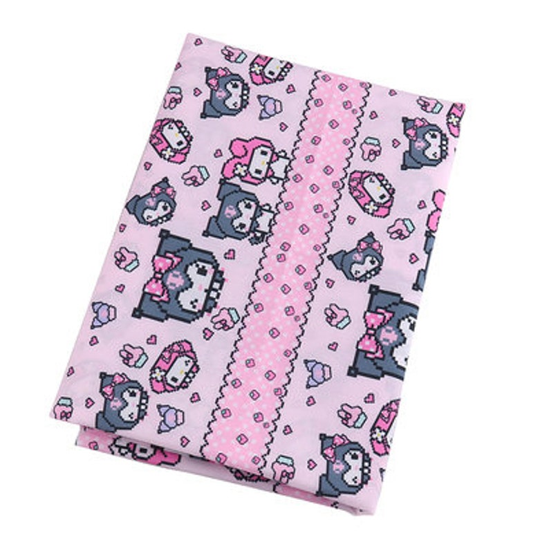 Op de afbeelding: Roze stof met een herhalend patroon van zwarte en roze cartoonfiguren. De stof heeft een witte kantversiering langs de randen.