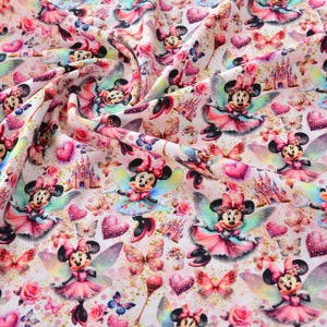 Puede incluir: Tela rosa con un patrón repetido de un ratón de dibujos animados con un vestido rosa y alas. El ratón está rodeado de mariposas, corazones y purpurina. La tela es perfecta para proyectos de manualidades, como hacer ropa, bolsos o decoración del hogar.