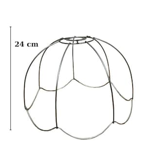Könnte beinhalten: Metall-Lampenschirmrahmen, 24 cm hoch und 35 cm breit, mit einem abgerundeten, blütenblattartigen Design. Der Rahmen besteht aus dünnen, silberfarbenen Metallstäben, die eine offene Struktur bilden. Ideal für DIY-Beleuchtungsprojekte.