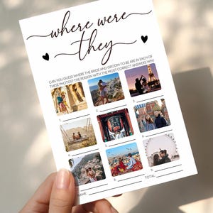 May include: A white card with the text "where were they" and nine small photo squares. The card is designed as a game for a wedding, with space to write answers. The card is held by a person.