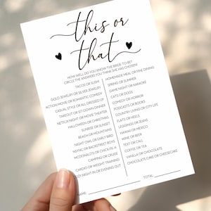 May include: A white card with the text "this or that" in a script font, with a list of questions below. The card is held by a hand. The questions include tacos or sushi, and cats or dogs.