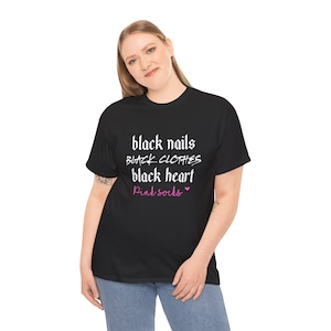 May include: Black t-shirt with the text "black nails BLACK CLOTHES black heart Pink socks" in a white and pink font. The shirt is worn by a person wearing blue jeans.