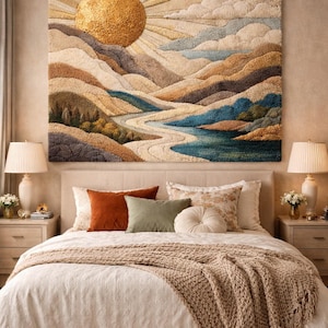 Op de afbeelding: Een grote rechthoekige wandhanger met een getextureerd, getuft landschapsontwerp. Het kunstwerk toont een gouden zon die opkomt boven gelaagde bergen, glooiende heuvels en een kronkelende rivier in tinten blauw, beige, bruin en cr&egrave;me.