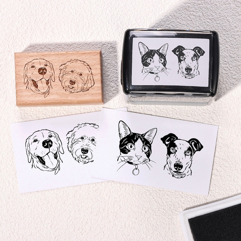 May include: A set of four custom pet portrait stamps. The stamps are made of wood and feature black and white illustrations of a cat, a labrador retriever, and two other dogs. The stamps are arranged in a grid pattern on a white background.