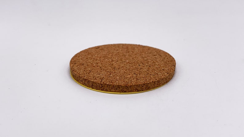 May include: A round cork coaster with a gold trim. The coaster is made of natural cork and has a rough texture.