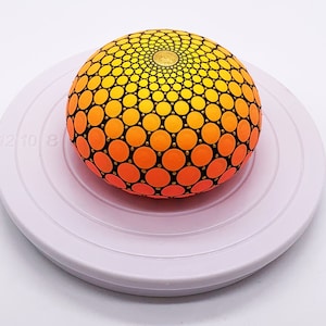 Peut inclure: Objet décoratif sphérique peint à la main avec un dégradé de points jaunes à orange. Il est posé sur un plateau rotatif circulaire blanc. Le motif présente un motif de points dorés au centre.