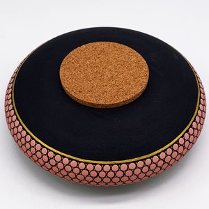 May include: Black ceramic bowl with a pink and gold geometric pattern. The bowl has a cork lid.