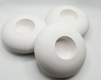 May include: Three white ceramic candle holders with a circular opening in the center. Each holder has the letters "HDC" embossed on the bottom.