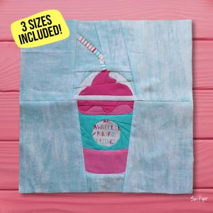Puede incluir: Un bloque de acolchado de papel con un slushie rosa y blanco con una pajita a rayas azul y blanca. La taza de slushie tiene un diseño estampado azul y blanco con el texto "Strawberry Playful Picnics".