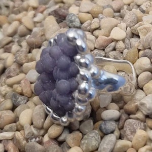 May include: A silver ring with a purple grape agate stone set in a beaded bezel.