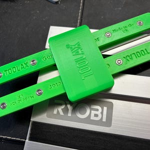 May include: Bright green TOOLAX guide tool. The tool is made in the UK and has the TOOLAX logo printed on it. The tool is designed to be used with a RYOBI tool.
