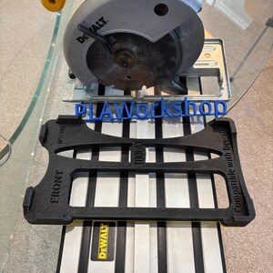 May include: A silver and black circular saw with a yellow handle is displayed above a black 3D-printed tool holder. The holder has the text "FRONT" and "Compatible with Dewalt". The text "DLAWorkshop" is also visible.