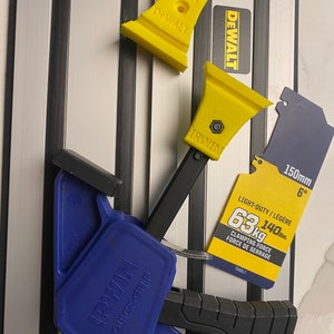 Könnte beinhalten: Eine blaue Irwin Quick-Grip-Klemme mit einem schwarzen Griff und einem gelben Irwin- und DeWalt-Markennamen auf der Klemme. Die Klemme befindet sich auf einer silbernen und schwarzen Oberfläche mit einem gelben Etikett mit der Aufschrift "Light-Duty/Légère 63kg 140lbs Clamping Force Force de Serrage 7548EL7 150mm 6" "