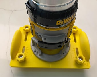 May include: Yellow and black router base with a depth gauge and a black and silver router attached. The router base has a DEWALT logo on it.