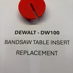 May include: Red plastic insert for a DeWalt DW100 bandsaw table. The insert is shaped like a circle with a slot cut out of it. The text "DEWALT - DW100 BANDSAW TABLE INSERT REPLACEMENT" is printed on a white background.