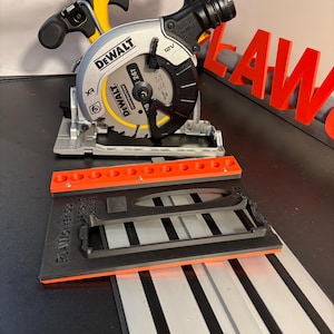 May include: A silver and black DeWalt 12V cordless circular saw with a yellow handle and a black and orange guide rail. The saw is on a black and silver surface.