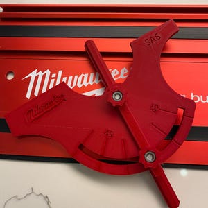 Puede incluir: Herramienta de plástico roja con un dial circular marcado con números y la palabra "SAS". La herramienta está etiquetada como "Milwaukee" y tiene una perilla para ajustar el ángulo.