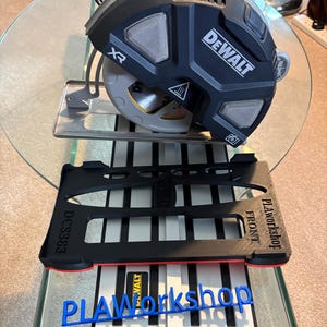 May include: A black and yellow DEWALT XR circular saw with a silver blade, resting on a black and red PLA Workshop stand. The stand has the text "FRONT" and "DCS383". A blue "PLA Workshop" logo is visible.