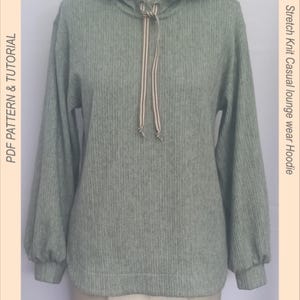May include: A sage green hoodie with a drawstring hood and long sleeves. The text "Myrtle's Dream 22011" is at the top. The text "PDF PATTERN & TUTORIAL" is on the left. The text "Stretch Knit Casual lounge wear Hoodie" is on the right. Sizes XS-XL are listed.