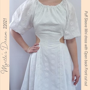 May include: White eyelet mini dress with puff sleeves and an open back and front cut out. The dress has a gathered neckline and a fitted bodice. The text "Mystle's Dream 22021" is written vertically on the left side of the image.