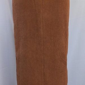 May include: A brown corduroy skirt with a high waist and a slight flare at the hem. The skirt has a vertical ribbed texture and a zipper closure in the back. The skirt is a solid color and appears to be made of a soft fabric.