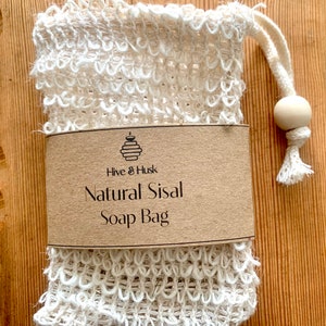 May include: A white natural sisal soap bag with a brown paper label that reads "Hive & Husk Natural Sisal Soap Bag".