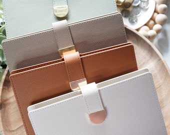 Puede incluir: Cuatro cajas de joyería apilables con un cierre dorado y un acabado texturizado similar al cuero. Las cajas son en tonos de verde, beige, marrón y blanco.