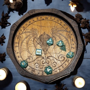 May include: Wooden dice rolling tray with a dragon design, featuring a dark brown octagonal frame. The tray's interior is light brown with a dragon engraving and several green dice with gold numbers. The tray is surrounded by lit candles.