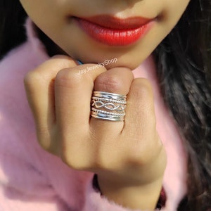 May include: A silver ring set with multiple bands, including a twisted band, worn on a finger. The ring is made of sterling silver and is a popular choice for everyday wear.
