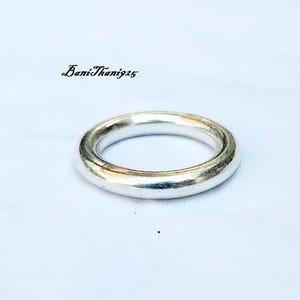 May include: A silver ring with a smooth, rounded surface.