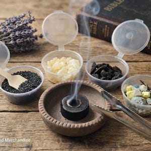 May include: An assortment of incense ingredients in small, clear containers with hinged lids. A lit charcoal disc in a small, brown bowl emits smoke. A sprig of lavender and a Bible are in the background.