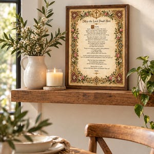 Pode incluir: Uma impressão de arte de parede emoldurada com o texto May the Lord Dwell Here, rodeada por uma borda decorativa de flores e uma cruz. O fundo estilo pergaminho contém uma oração em fonte preta, dentro de uma moldura de madeira castanho-escura.